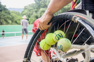 Pelotas de tenis colocadas en la rueda de un atleta especial