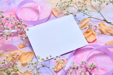 white card, background for greeting card women's day, Valentine's day. White flowers, yellow rose Petals, pink ribbons lie on a watercolor background in delicate pink, blue, yellow shades