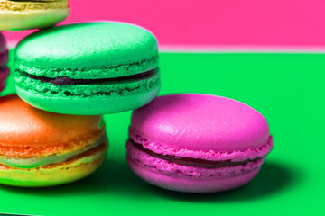 Closeup of delicious and fresh French baked macaroon on a colorful green and pink background