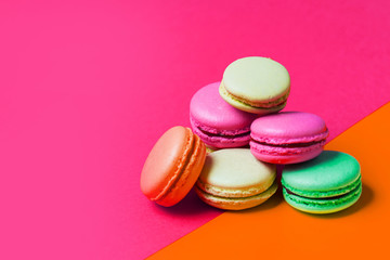 Fototapeta na wymiar Cake macaron or macaroon on pink and orange background with copy space, closeup