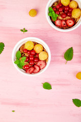 Healthy breakfast on white bowls. Fresh granola, muesli or cereal with berries