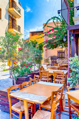 Fototapeta na wymiar Sunny Open Air Cafe in Chania City on Crete. With Flowers and Olive Trees All Round in Crete, Greece.