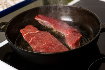 frying beef steaks on a cast-iron pan