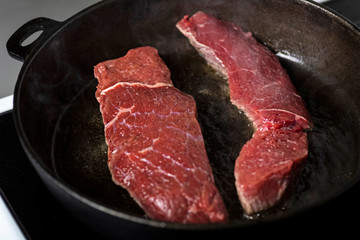 frying beef steaks on a cast-iron pan