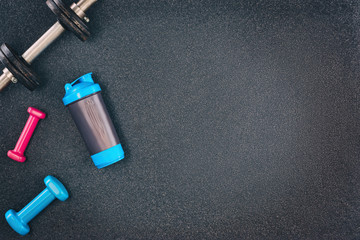 Obraz na płótnie Canvas Fitness or bodybuilding concept background. Product photograph of old iron dumbbells on black grey, conrete floor in the gym. Photograph taken from above, top view with lots of copy space