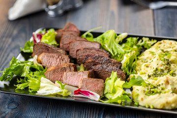 Pieces of meat on lettuce with mashed potatoes