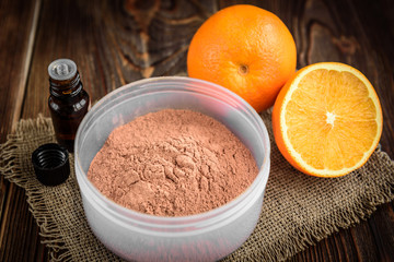 Pink cosmetic clay, essential oil and oranges on dark wooden background. Ingredients for mask- cosmetic clay, aroma oil, orange. Homemade skincare. 