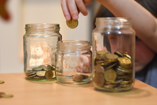 Boy putting coins in a glass jar. Concept of saving. Child save money for Christmas presents