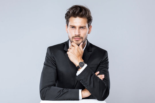 Handsome man in black suit with luxury watch looking straight