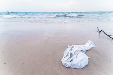 Fototapeta na wymiar White plastic bag rubbish dump on sand sea beach from deep sea after finish strong wind.Thailand.