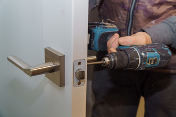 Install the door handle with a lock, Carpenter tighten the screw, using an electric drill...