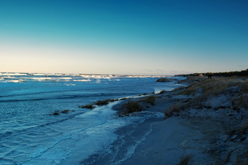 Blue winter seascape ocean view of the Baltic Sea with waves and dunes and blue color tones during winter Storm flood tide. German Baltic Sea coastline at Fischland-Darss-Zingst in Mecklenburg