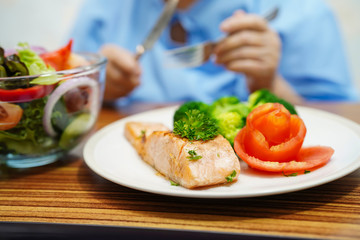 Asian senior or elderly old lady woman patient eating breakfast healthy food with hope and happy while sitting and hungry on bed in hospital.