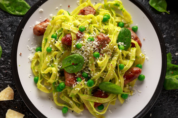 Homemade Pasta with green peas, spinach pesto and sausages. parmesan cheese. healthy food. background