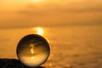 Crystal ball on the beach with sea waves at morning sunrise.Thailand.