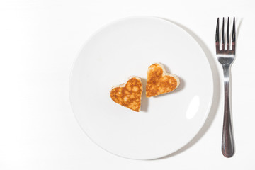 plate of pancakes in the shape of heart and forks on white background