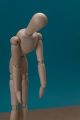 Wooden mannequin. Sadness concept. Blue background.