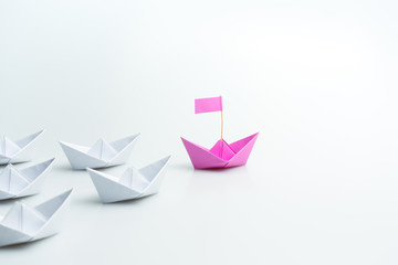 Woman Leadership concept with pink paper ship leading among white on white background.