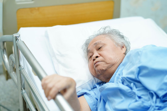 Asian Senior Or Elderly Old Woman Patient Lie Down Handle The Rail Bed With Hope On A Bed In The Hospital.