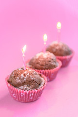 Chocolate cupcakes with candle on pink background.