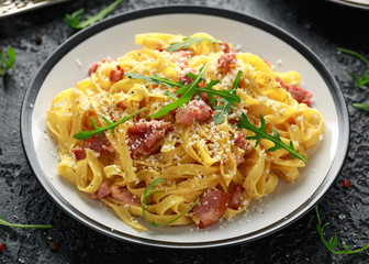 Classic Carbonara pasta, spaghetti with pancetta, bacon, egg, parmesan cheese and green arugula.