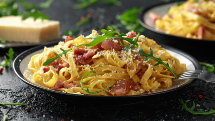 Classic Carbonara pasta, spaghetti with pancetta, bacon, egg, parmesan cheese and green arugula.
