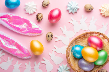 Easter holiday background. Easter eggs colored with rabbit ears on a pink background with sweets. Flat lay, horizontal composition. Greeting card concept