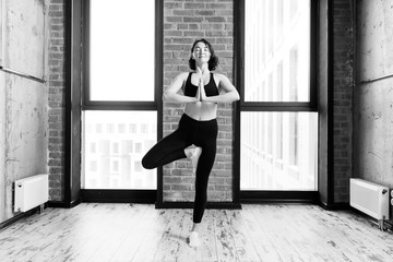 cheerful motivated woman is standing on one leg and practising yoga. black and white photo.motivation and health care