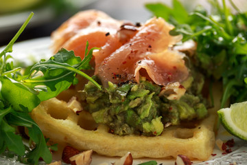 Potato waffles with avocado guacamole and smoked salmon for breakfast