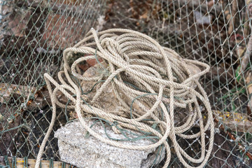 Gray sea ropes lie in a heap in fishing port.Thailand.