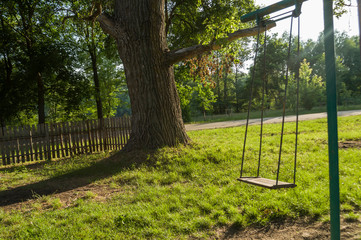 Childrens playground on the yard in summer. Rest with little child. swing in the park