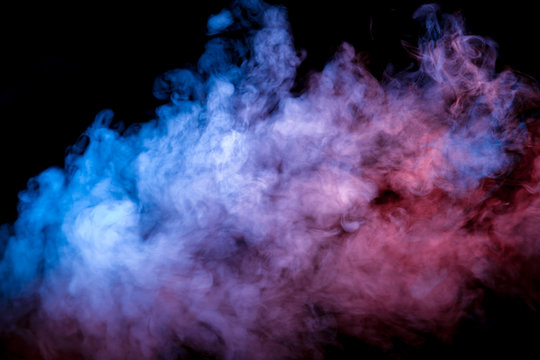 Clouds of isolated colored smoke: blue, red, orange, pink; scrolling on a black background in the dark close up.