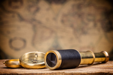 antique spyglass and compass on old map background - obrazy, fototapety, plakaty