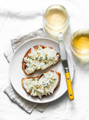 Pear, blue cheese, thyme sandwiches and white wine - delicious aperitif on a light background, top view