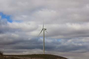 wind turbines in the field against blue cloudy sky, electric generators in countryside