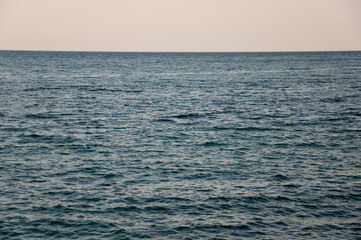 Obraz premium Black Sea. Water with no waves and little boat far away. Calm. Mainly cloudy weather. Blue and grey color. Before rain
