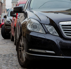 Obraz na płótnie Canvas Close-up headlight of black modern car with other cars on background