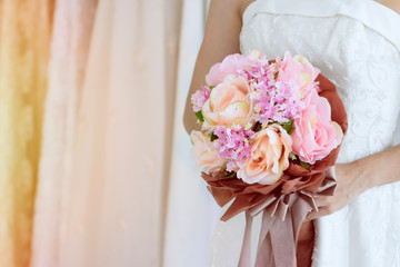 Fototapeta na wymiar Wedding concept; wedding bouquet in bride's hands.Beautiful tender wedding bouquet of cream roses flowers in hands of the bride.