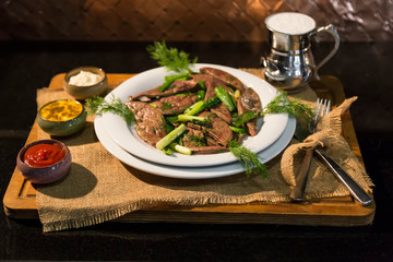 lamb liver food with green vegetables in the plate and local bread on the wooden table for restaurant and kitchen concept.