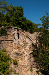 Old ancient destroyed stone house on the yard with trees around. Poverty and misery, South, summer 