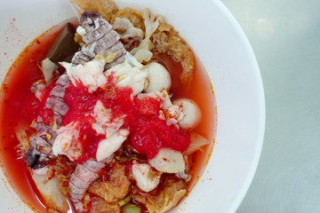 Yentafo Spicy noodle soup,hot and spicy ,with mix seafood, crayfish, shrimp. Asian spicy seafood noodle soup in white bowl on table background. Thai style noodle and street food of Thailand.