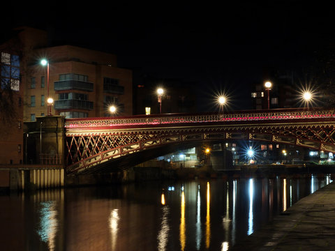 crown point bridge crossing the river aire in leeds at night with lights and surrounding buildings reflected in the water