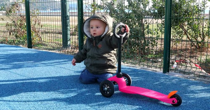 Cute Baby Boy Playing With A 3 Wheel Scooter On A Playground. Close Up View Portrait - DCi 4K Resolution