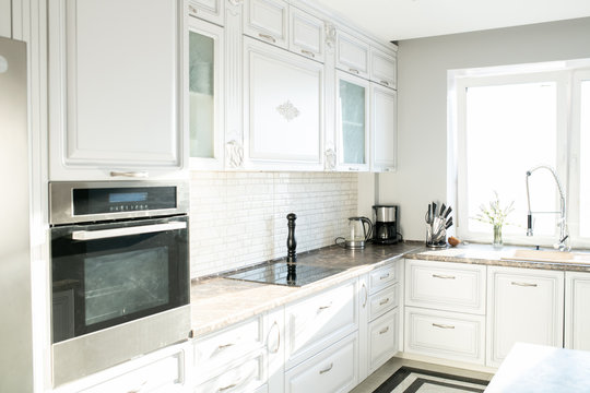 Background image of empty white kitchen with modern design and appliances lit by sunlight, copy space