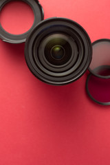 Professional photography lenses and accesories over red background with copy space. Top view.