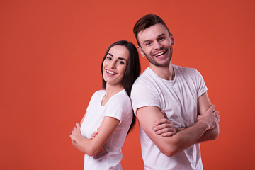 Obraz premium Happy and excited couple are posing in white t-shirts on orange background