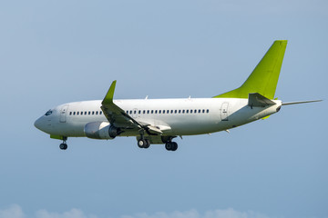 Fototapeta na wymiar White passenger airplane with green tail landing.