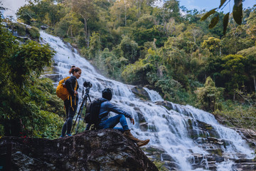 Asian couple travel nature. Travel relax. Stand landscapes Natural Touch Stand to see beautiful waterfalls mae ya at Chiangmai in Thailand.