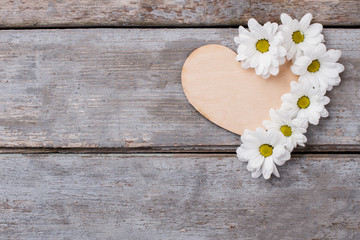 Fototapeta premium Wooden heart with white chamomile flowers composition. Top view. Old rustic wooden table.