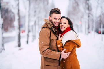 Close up photo of happy young beautiful couple in love while they hugging, kissing and have a fun outdoors in winter city park